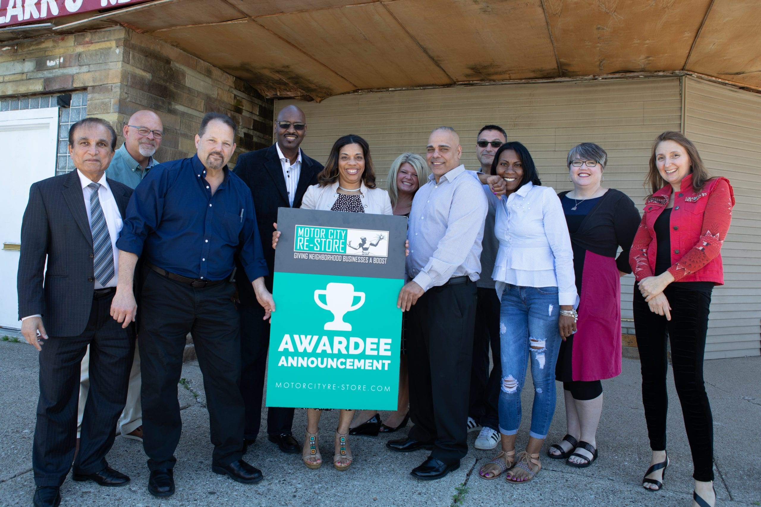 A group of people posing for a picture while holding up an awardee sign