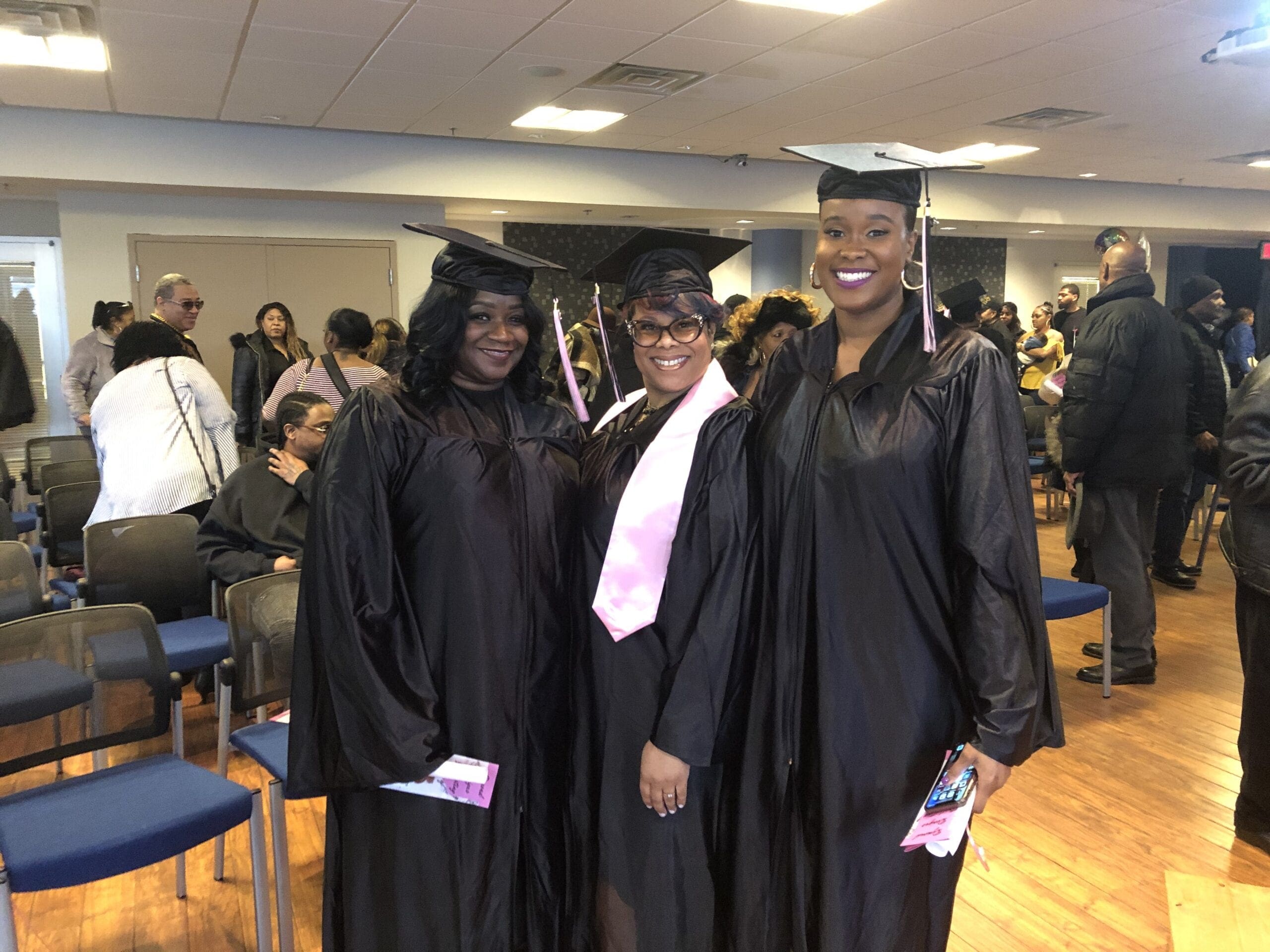 Three new graduates posing for a picture in their black cap and gown